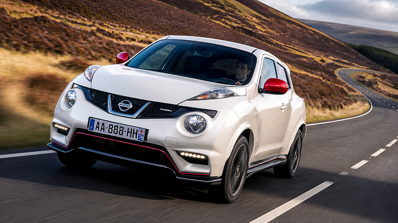 Carro branco Nissan Juke Nismo dirigindo em estrada sinuosa com colinas ao fundo.