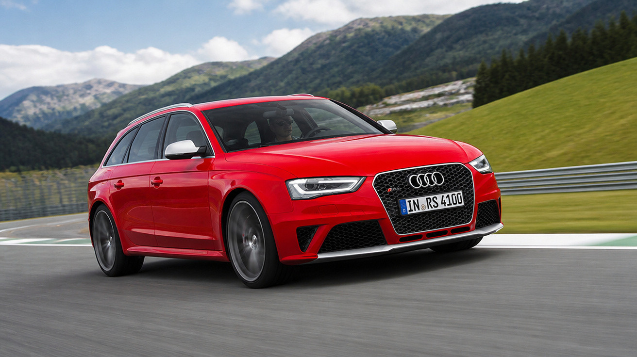 Carro esportivo Audi RS4 Avant vermelho em alta velocidade em pista com montanhas ao fundo.