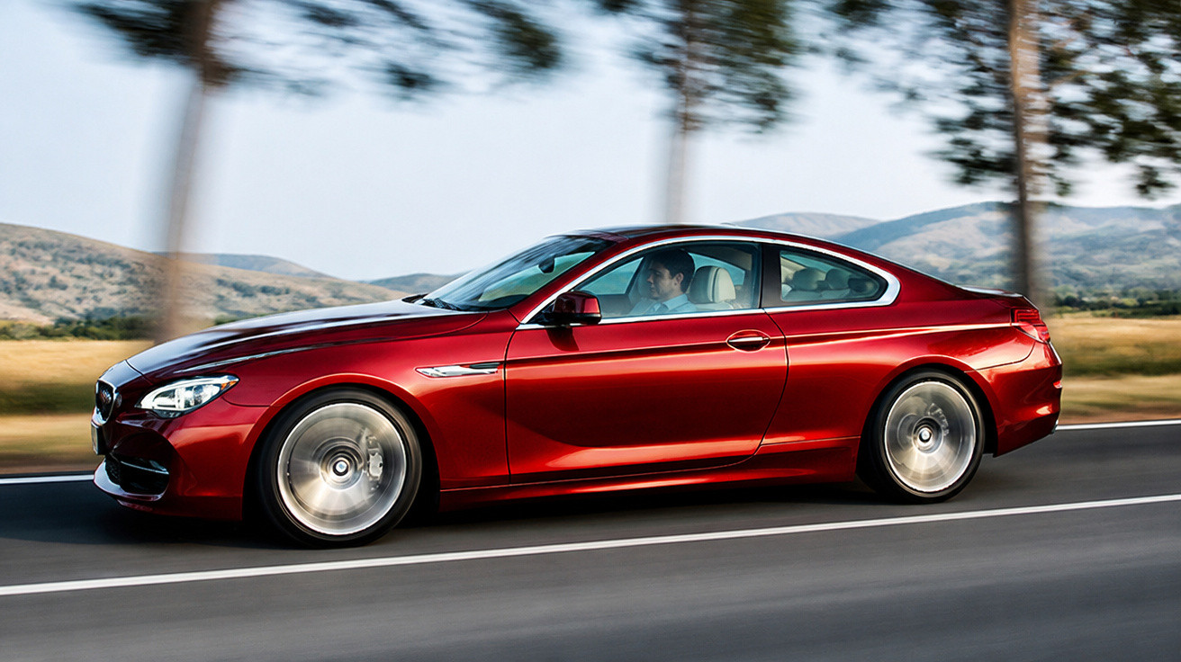 Carro esportivo vermelho em alta velocidade na estrada com árvores e montanhas ao fundo.